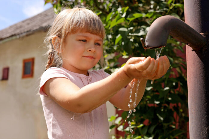 Water scarcity. Cute little girl drawing water with hands from t